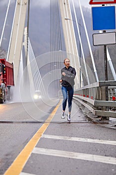 Sporty woman warms up on countryside bridge, jogging. Healthy lifestyle concept