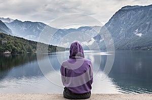 Sporty woman watching tranquil overcast morning scene at lake Bohinj, Alps mountains, Slovenia.