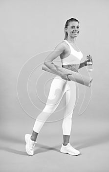 Sporty woman with yoga mat. Young fitness woman runner stretching legs before run. Sport and healthy lifestyle.