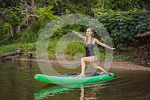 Sporty woman in yoga position on paddleboard, doing yoga on sup board, exercise for flexibility and stretching of