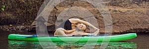 Sporty woman in yoga position on paddleboard, doing yoga on sup board, exercise for flexibility and stretching of