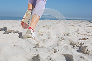 Sporty womans feet jogging on the sand