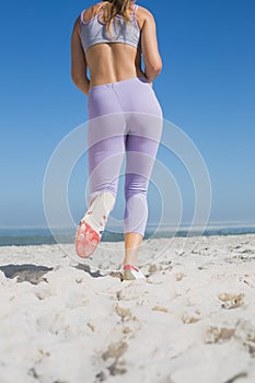 Sporty womans feet jogging on the sand