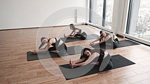 Sporty women sitting in Head to Knee pose in yoga studio