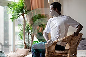 Sporty young african man practicing yoga using chair, doing Revolved Chair Pose, Parivrtta Utkatasana