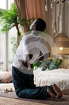 Sporty young african man working out, yoga, pilates or fitness training, standing in asana ushtrasana