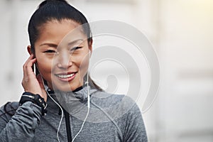 Sporty young Asian woman listening to music before a jog