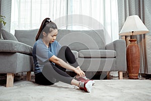 Sporty young asian woman sitting wear her shoes to prepare for exercise at home in the living room