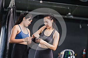 Sporty young asian women training boxer preparing strap on wrist with coach trainer