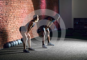 Sporty young couple with dumbbells on red brick wall background