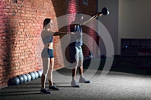 Sporty young couple with dumbbells on red brick wall background