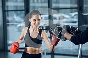 sporty young female boxer exercising with trainer