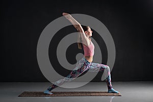 Sporty young girl practicing virabhadrasana warrior. Studio shot