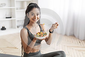 Sporty young indian woman eating fresh salad after workout