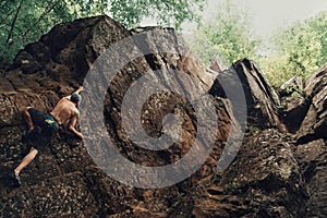 Sporty young man climbing on stone rock