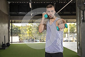 Sporty young man training with dumbbells with copy space