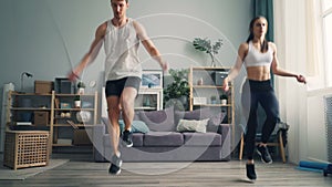 Sporty young people man and woman doing sports jumping rope together in flat