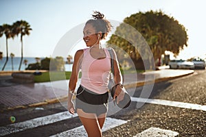 Sporty young woman crossing the street holding a yoga mat