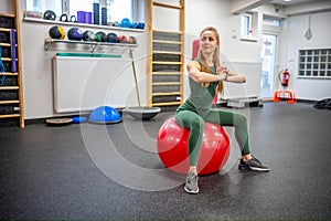 Sporty young woman doing exercise on fitball at gym.