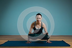 Sporty young woman doing stretching. Slim girl practicing yoga indoors on blue background. Calm, relax, healthy