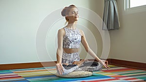 Sporty young woman doing yoga practice in the lotus position on mat in home ,  fitness girl workout in room