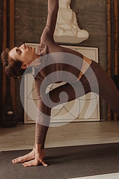 Sporty young woman doing yoga practice on yoga mat is in the yoga room. Vintage tonned. Concept of healthy life and natural