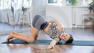 Sporty young woman doing yoga in studio, performing hamstring and low back stretching Ardha Pawanmuktasana