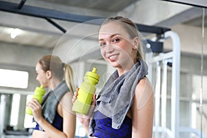 Sporty young woman drinking water at gym. Female drink water.  Beautiful young caucasian woman drinking water after doing fitness