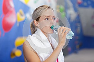 sporty young woman drinking water in gym