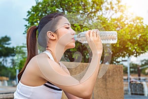 Sporty young woman drinking water after jogging