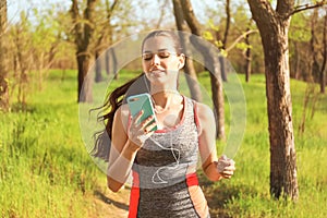 Sporty young woman listening to music while running in park