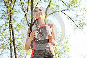 Sporty young woman listening to music while running in park