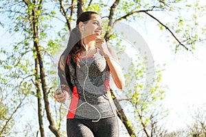 Sporty young woman listening to music while running in park