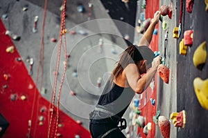 Sporty young woman training in a colorful climbing gym.