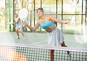 Sporty young woman playing padel on open court on summer