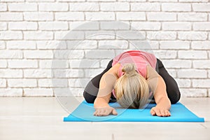 Sporty young woman practicing yoga on mat indoors