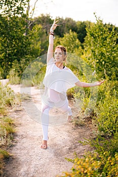 Sporty young woman practicing yoga on park outside the city. Meditative lady enjoying meditation