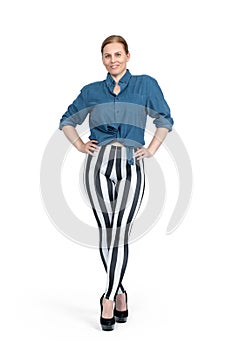 Sporty young woman in a shirt, striped leggings and stiletto heels, standing tall, isolated on a white background