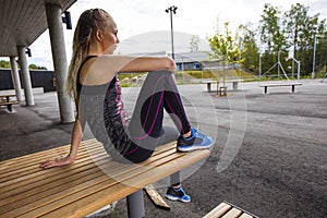 Sporty Young Woman Sitting On Wooden Bench At Park