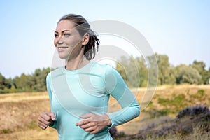 Sporty young woman in sportswear jogging, running and training outdoors on a sunny day in summer