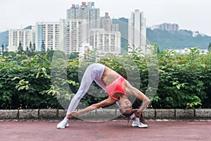 Sporty young woman stretching doing yoga triangle pose standing in wide-legged position bending to side. Fitness girl