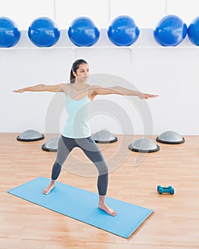 Sporty young woman stretching hands in fitness studio