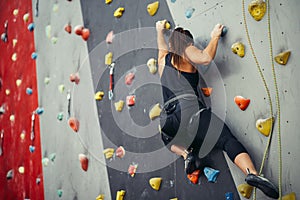 Sporty young woman training in a colorful climbing gym.