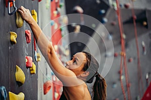 Sporty young woman training in a colorful climbing gym.