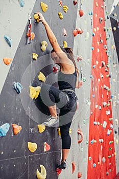 Sporty young woman training in a colorful climbing gym.