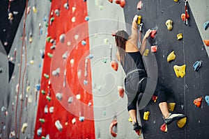 Sporty young woman training in a colorful climbing gym.