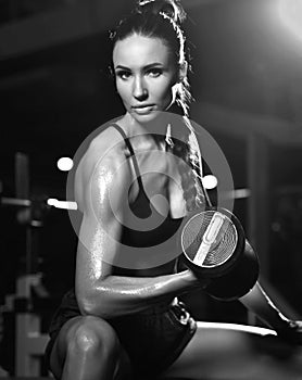 Sporty young woman working out with dumbbells weight in Gym. Diet and weight loss concept