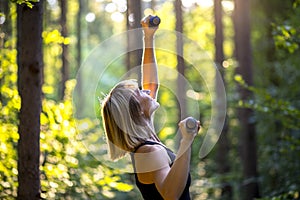 Sporty young woman working out with weights