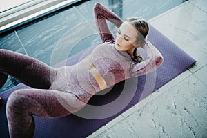 Sporty young woman on yoga mat doing situps in gym. Fitness woman doing abs crunches