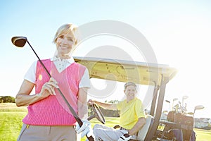 Spot of golf. Low angle shot of an attractive older female golfer standing in front of a golf cart with her golfing